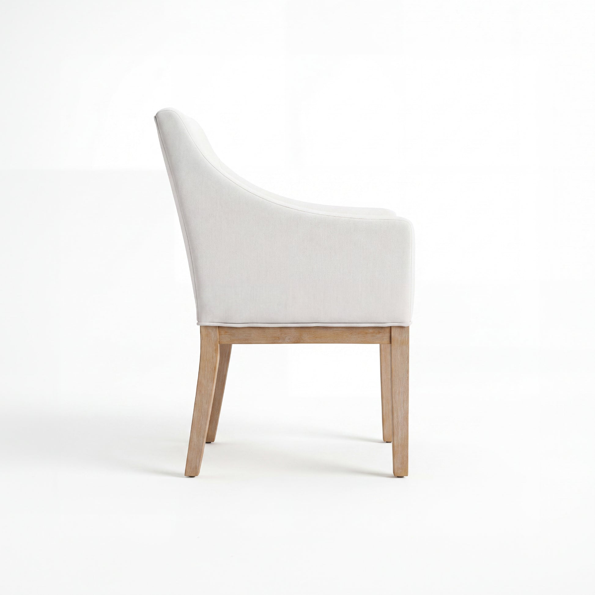 A modern dining chair with a light beige upholstered seat and curved backrest, supported by light natural wood legs, shown from a side profile on a white studio background.